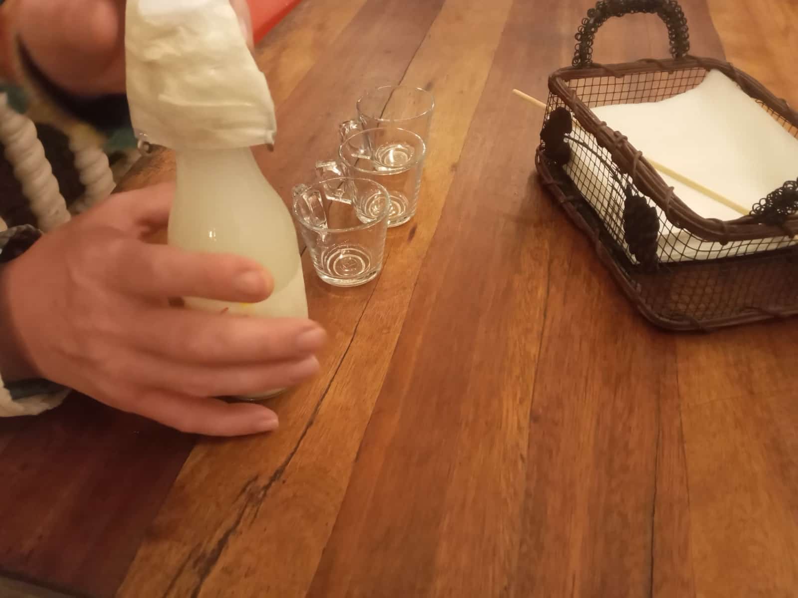 Sirviendo vino de palma en vasos pequeños sobre una mesa de madera