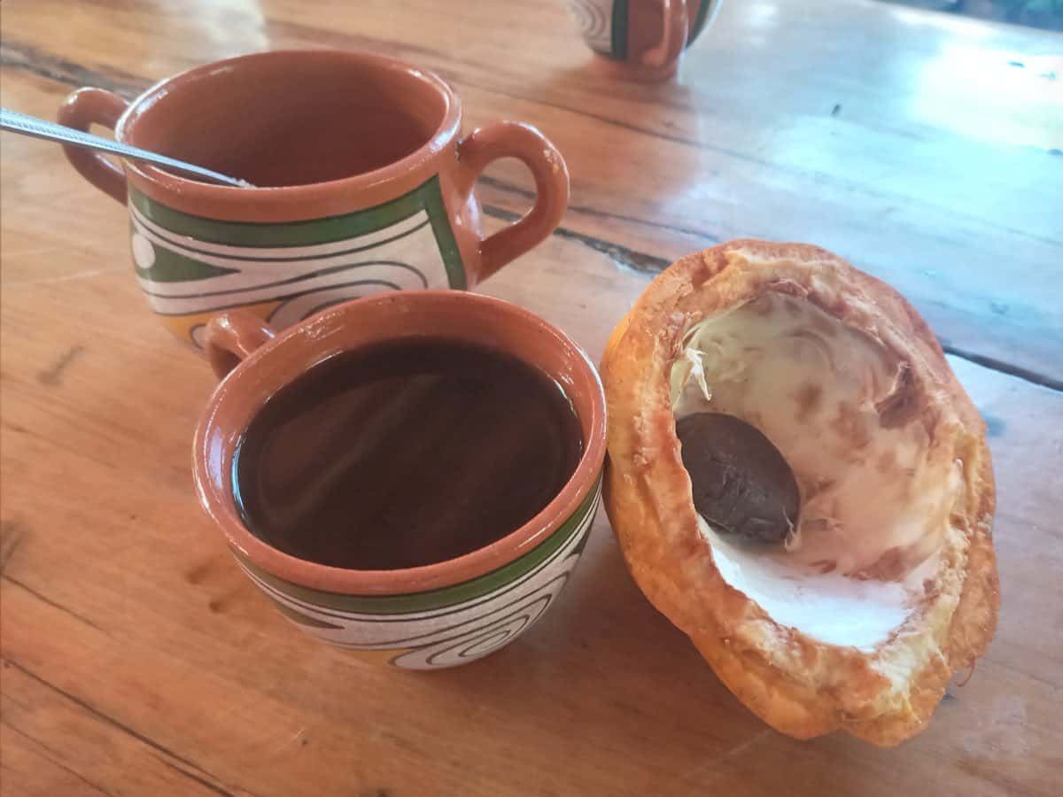 Dos tazas de barro pintadas con motivos verdes y naranjas, con la bebida de cacao dentro