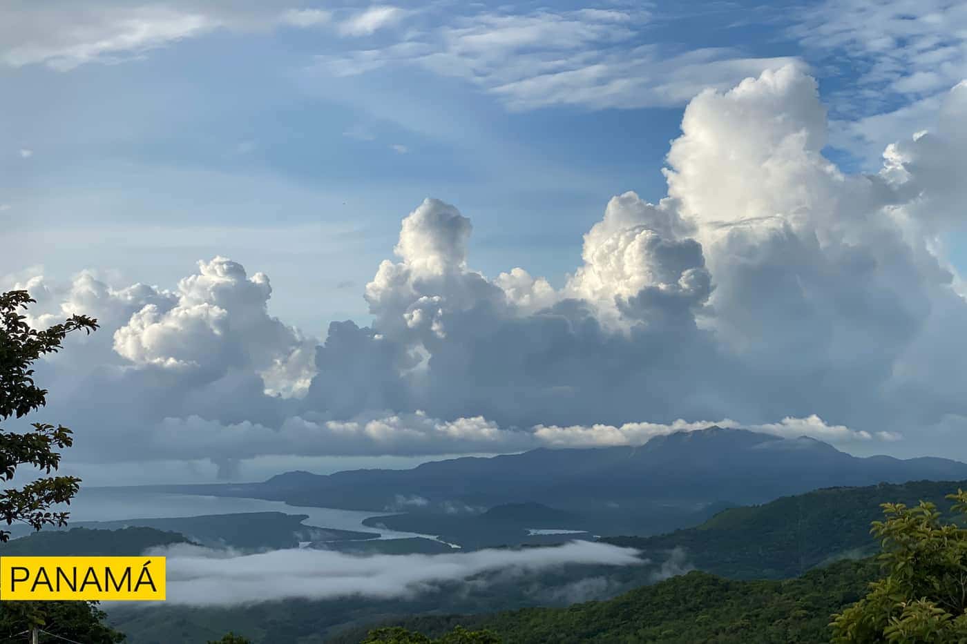 Nubes altas y blancas sobre una bahía, con montañas azules al fondo